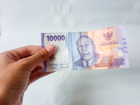 hand holding ten thousand rupiah banknotes, isolated white background