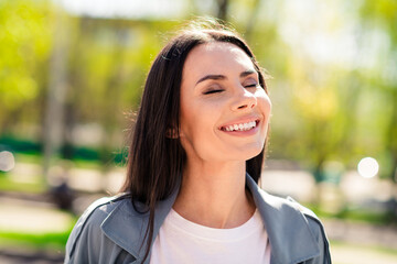 Fototapeta premium Portrait photo of beautiful young smiling latin attractive lady breathing fresh air wearing gray coat walking outdoors relaxed in nature