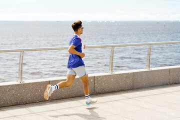 A Young Man Jogging Along a Waterfront Pathway on a Sunny Day With Calm Waters in the Background