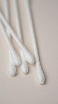 Cotton swabs close up orderly aligned on white background rotating in motion, vertical video
