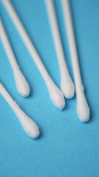 Cotton swabs close up on blue background rotating in motion, vertical video
