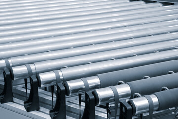 Machine machinery industrial roller metal conveyor close up in blue tones, industrial concept...
