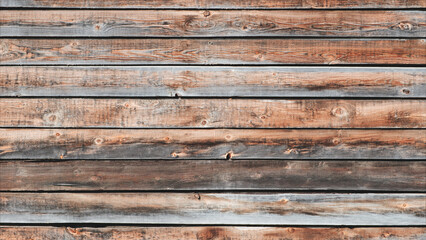 A wooden wall with a grainy texture. The wood is brown and has a natural look. The wall is empty and has no furniture or decorations