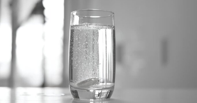 Effervescent aspirin pill in a glass of wate. Soluble tablet shot on super slow motion camera 1000 fps.
