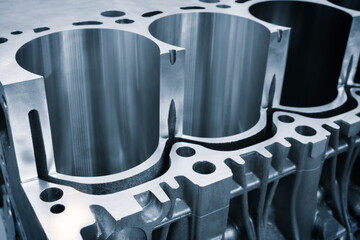 A close up of a car engine with cylinders. The cylinders are made of metal and have holes in them....