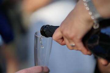 Champagner Sekt Wein Weinschorle wird aus der Flasche in ein Sektglas eingeschenkt