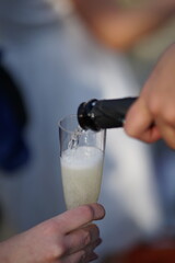 Champagner Sekt Wein Weinschorle wird aus der Flasche in ein Sektglas eingeschenkt