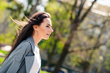 Fototapeta premium Portrait photo of beautiful young smiling latin attractive lady wearing gray coat walking outdoors windy weather in nature