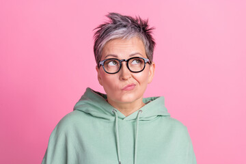 Photo of unsure attractive lady wear khaki hoodie looking empty space isolated pink color background