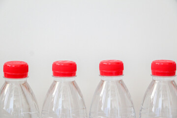Clear plastic bottled water with red caps lined against white background. Healthy lifestyle and hydration concept.