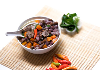 Sup daging kacang merah, clear soup with beef slices, red bean and vegetables. Served in bowl on wooden background. Selected focus.