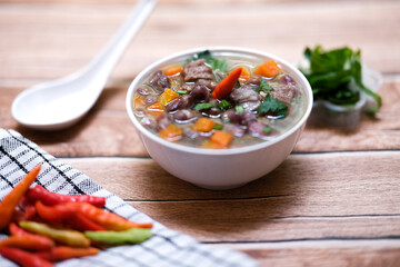 Sup daging kacang merah, clear soup with beef slices, red bean and vegetables. Served in bowl on wooden background. Selected focus.