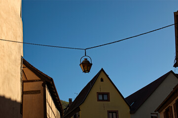 Tiled roof of medieval houses against blue sky.City lamp hangs on metal chain. Abstract cityscape...