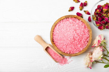 Sea salt for bath with aroma and rose flowers on textured wooden background. Pink sea salt. Spa treatments. Natural salt with herbs and essential oils. skincare concept. Meso for text. Copy space