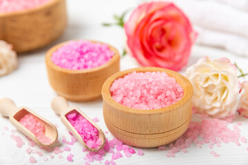 Sea salt for bath with aroma and rose flowers on textured wooden background. Pink sea salt. Spa treatments. Natural salt with herbs and essential oils. skincare concept. Meso for text. Copy space