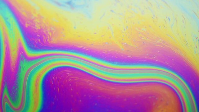 Close-up macro of colorful iridescent moving soap film surface, abstract vibrant rainbow colored pattern and texture background

