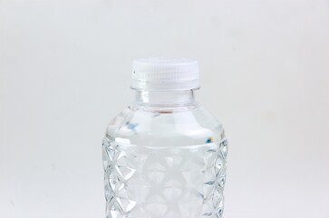 Close-up image of the top of a plastic bottle filled with water and its lid on a white background