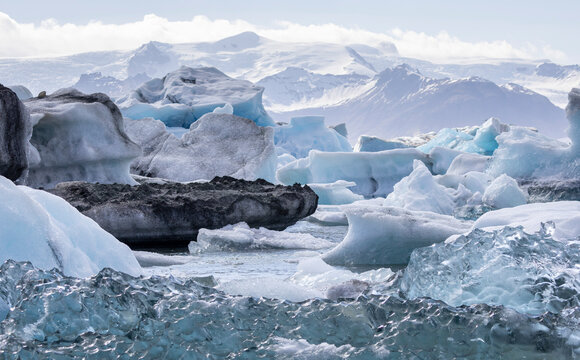 black, white and translucent icebergs in Jökulsárlón lagoon with  Vatnajokull ice cap in the background, Iceland