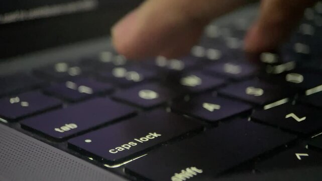 Close-up of finger pressing a key on a black laptop keyboard.