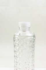 Close-up image of the top of a plastic bottle filled with water and its lid on a white background