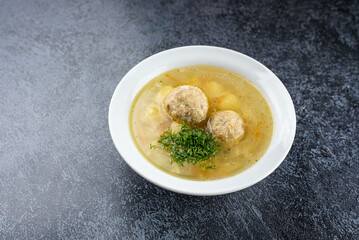 Homemade soup with meatballs and greens on a gray background