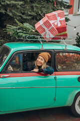 Young blonde woman sitting in retro car with Christmas decorations