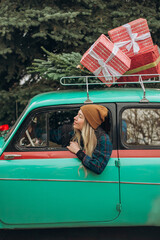 Young blonde woman sitting in retro car with Christmas decorations