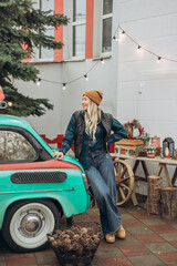 Young blonde woman near retro car with Christmas decorations