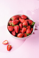 strawberries in a bowl on a pink background
