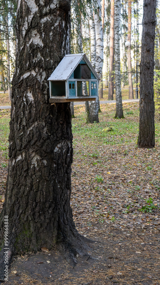 Poster a birdhouse is hanging from a tree in a forest