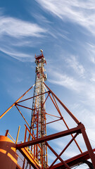 A tall tower with a red top is seen against a blue sky