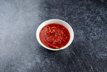 A bowl of red sauce with a pepper on top