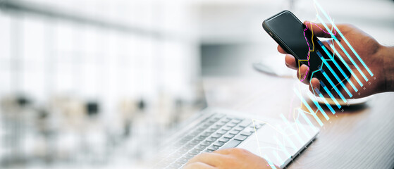 Closeup of hands using smartphone and laptop with financial graphs overlay in a modern office.