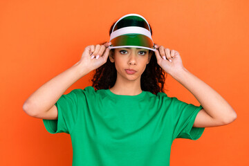 Naklejka premium Photo of young funky attractive confident expression girl touch her green stylish summer cap isolated on orange color background