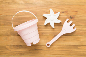 Cute toys for playing with sand on wooden background, top view