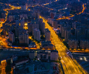 Aerial view of highway junctions with roundabout. Bridge roads shape circle in structure of architecture and transportation concept. Top view. Urban city, Shanghai at night, China