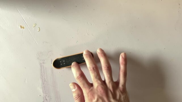 top shot of awesome flip trick while fingerboarding, male hands on finger board, 4k footage, an ollie performed at the front of the board.