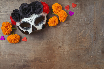 Day of the dead Mexican and Halloween holiday concept. Sugar skull mask and flowers on rustic  background. Top view, flat lay