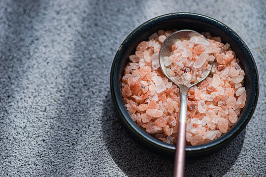 Overhead view of a bowl of pink Himalayan salt on a table in sunlight