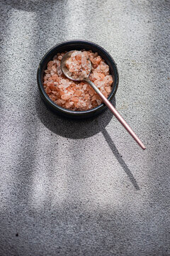 Overhead view of a bowl of pink Himalayan salt on a table in sunlight