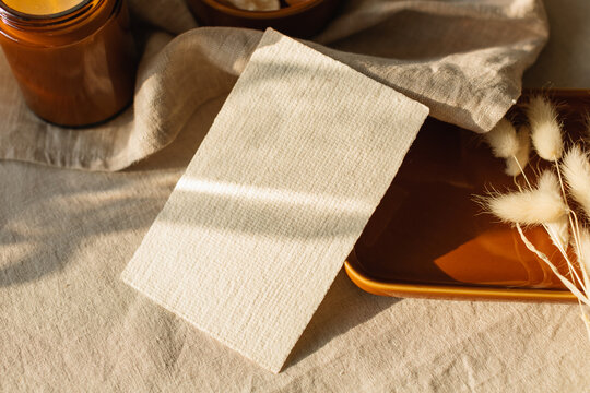 Close-up of a blank piece of card on a table with hare's tail grass (Lagurus) and a candle