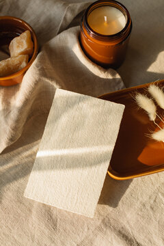 Overhead view of a blank piece of card on a table with hare's tail grass (Lagurus) and a candle