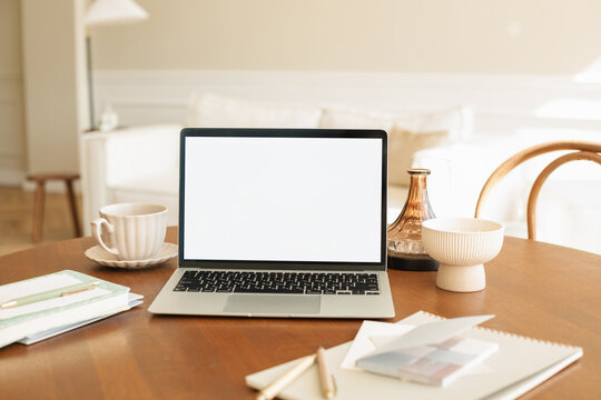 Close-up of a Laptop with a blank screen on a dining table with a cup of tea and assorted stationery