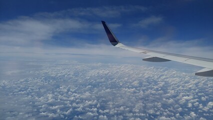 view of clouds with blue sky from behind the plane window