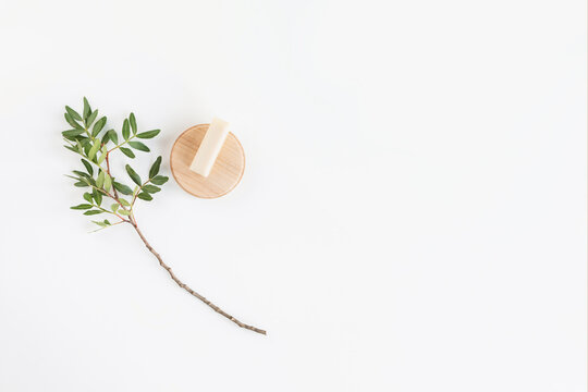 Overhead view of a pistachio branch and a bar of soap on a white background