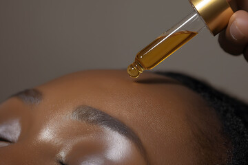 Close-Up Shot of Oil Dropper Applying Oil to Hydrated Black Woman's Scalp