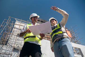 Contractor and engineer architect working together planning using blueprint design structure construction industry, building house innovation and teamwork discussing, two male caucasian collaborating.