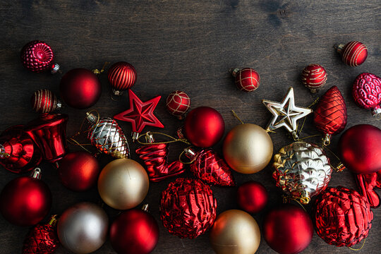 Overhead view of assorted red, gold and silver Christmas baubles on a wooden table
