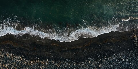 Aerial View of Dark Pebbled Beach and Deep Green Ocean with Foamy Waves