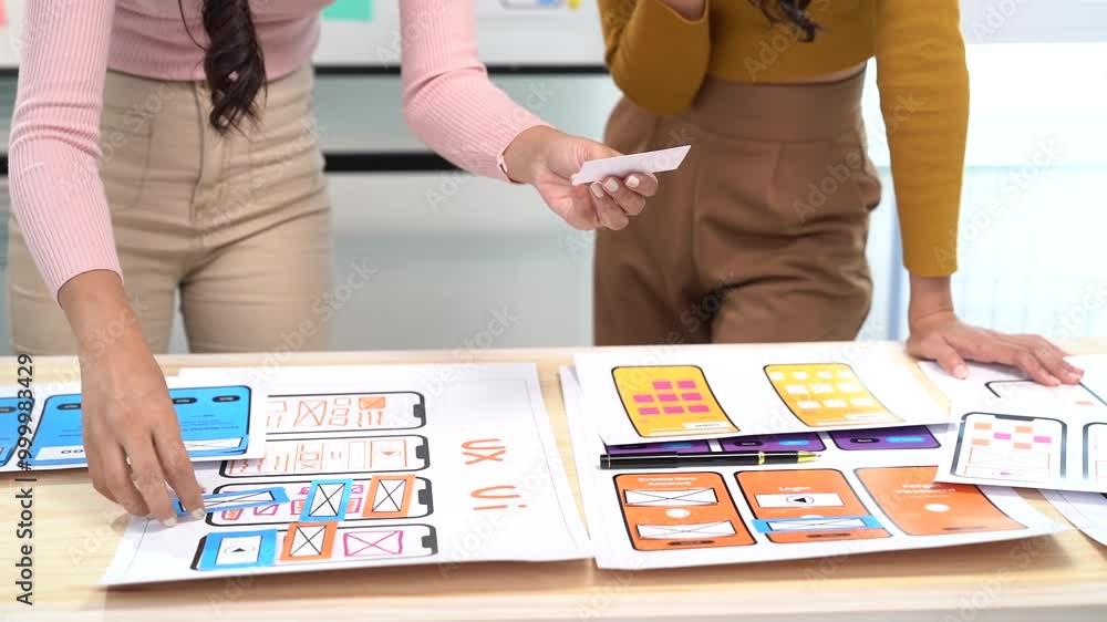 Wall mural two female web designers collaborating on a user interface for a mobile phone application. they are 